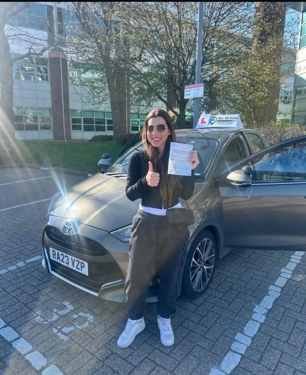 A happy Go Green Driving School learner holding their driving test pass certificate